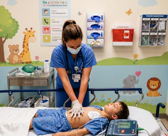 nurse performing cpr on chid with the help of aed